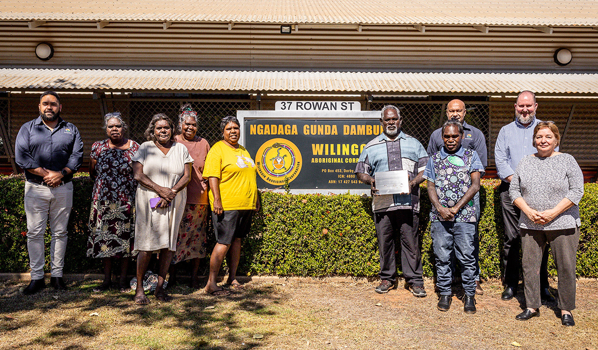 Ten people stand on both sides of a building sign