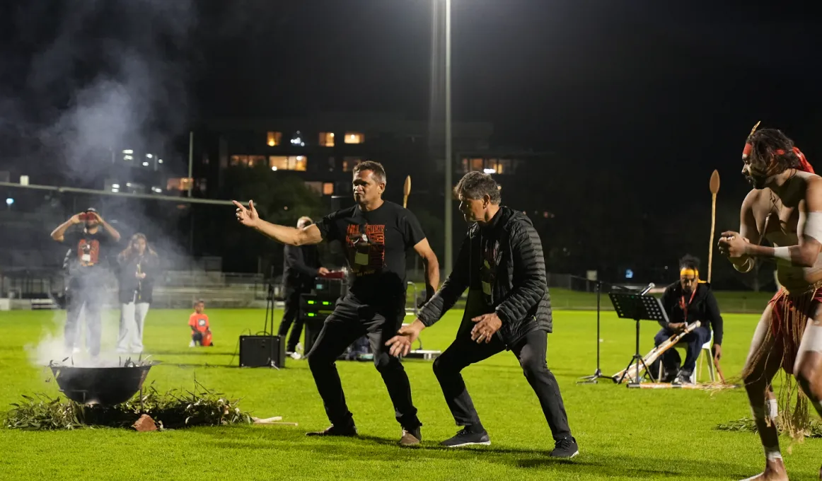 Indigenous men performing a Healing Ceremony on a football oval.