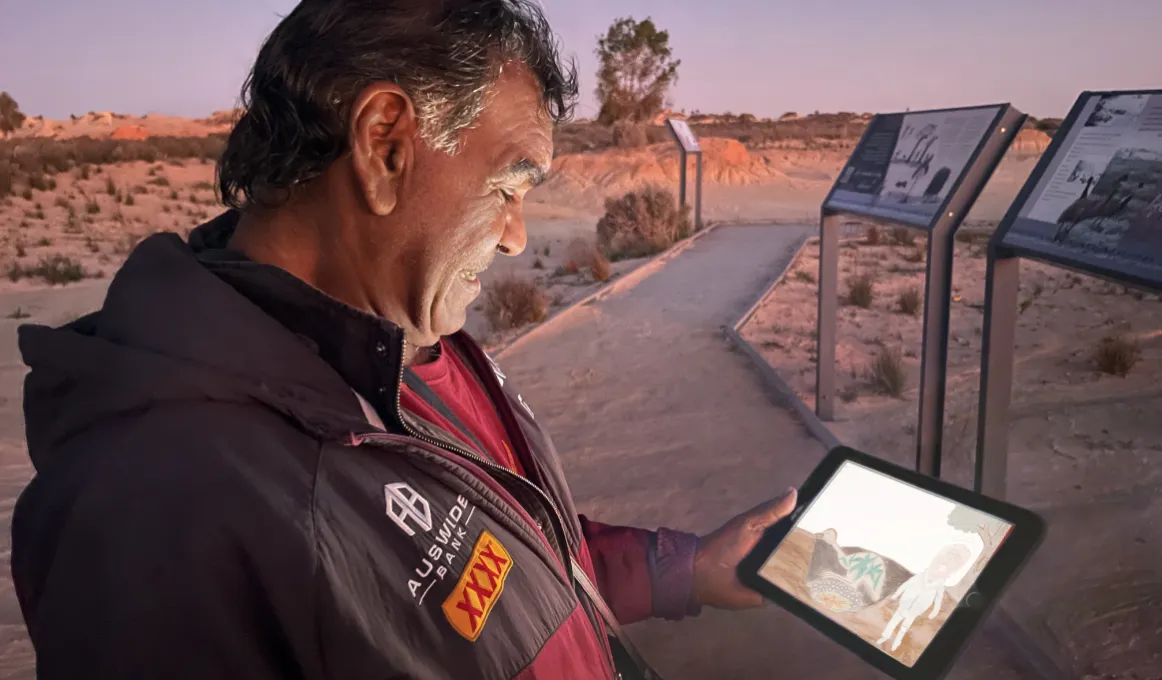 A man reads a computer tablet on a trail