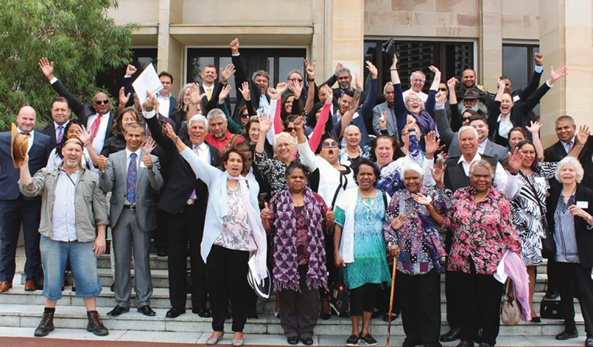 Group photo of people, some with their arms in the air on the steps outside the Parliament of Western Australia.