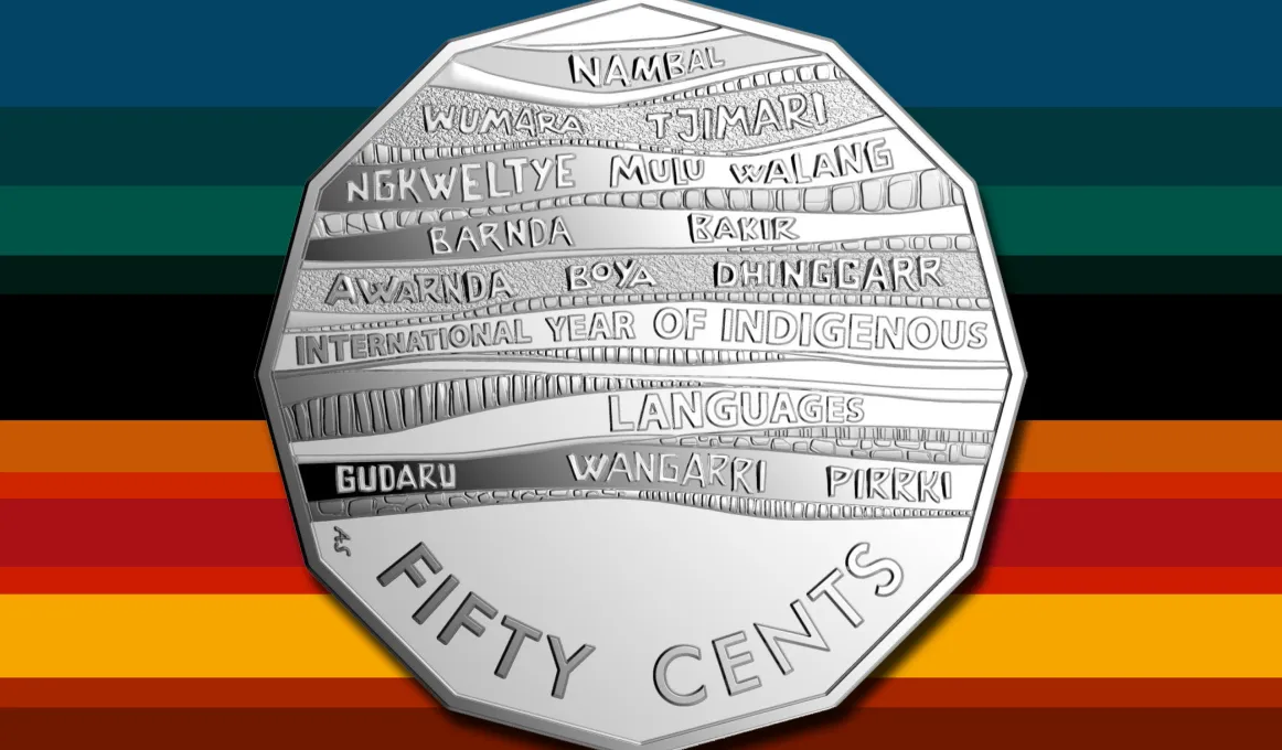 Silver sharp sided coin featuring the words Fifty Cents and multiple Indigenous Australian names on a background of horizontal stripes on many different colours.