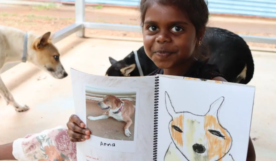 Eight-year-old Lorise Lee holds her drawing and story about her dog Arna in 'Our Barunga Dogs'.