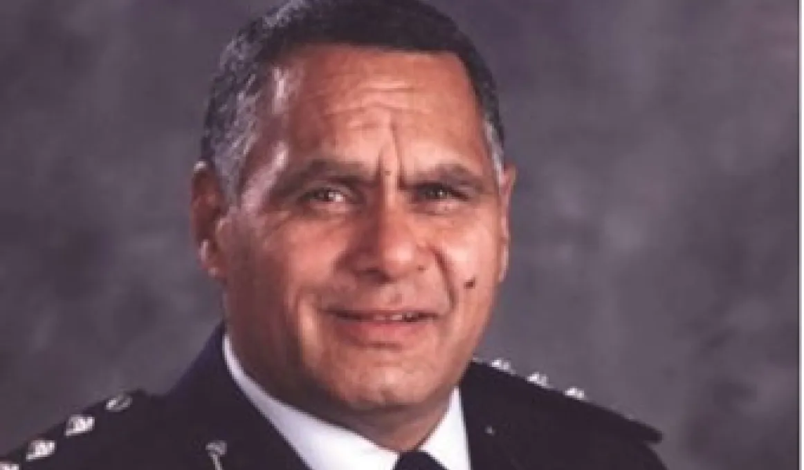 Head and shoulders shot of Indigenous man dressed in police officer’s uniform.