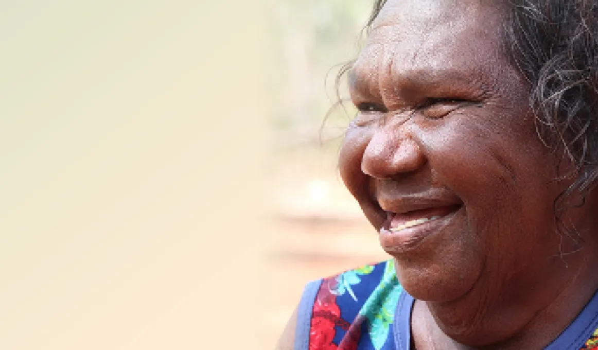 A smiling Aboriginal woman in a colourful top.