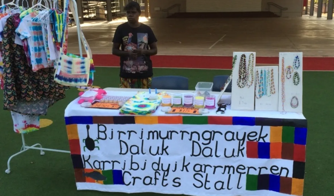 Jocelyn Koyole standing behind table of items for sale.