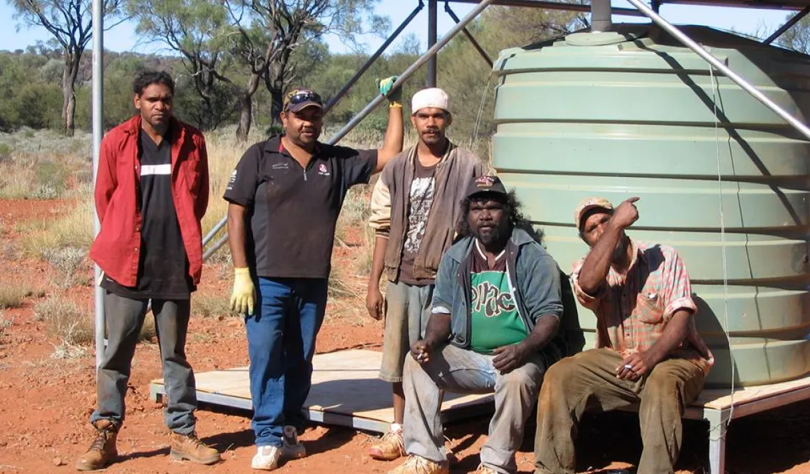 Five Indigenous men in front of a water tank