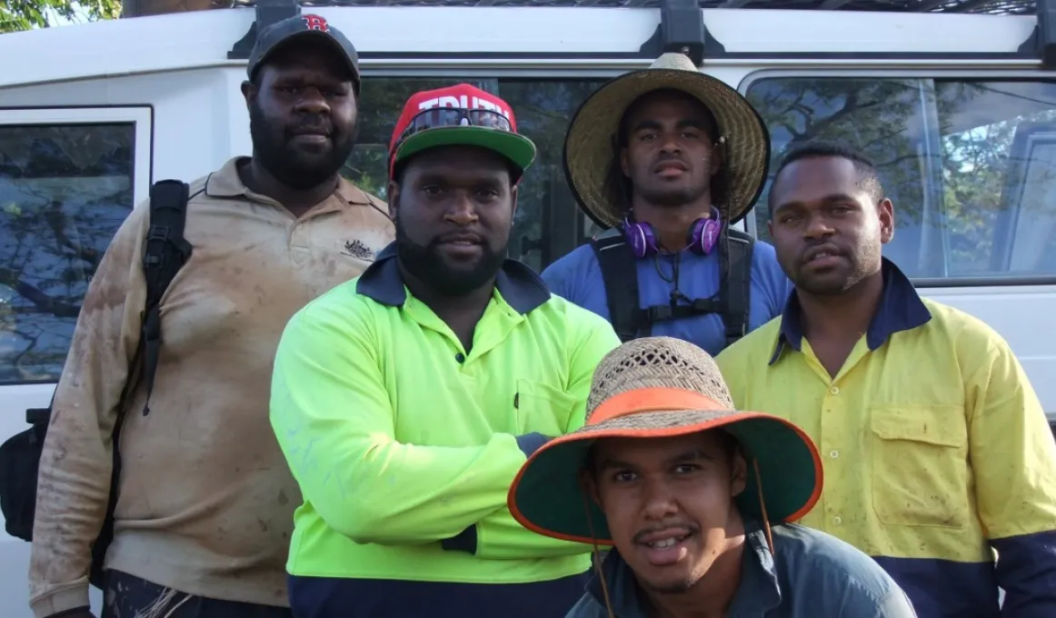 Five young Torres Strait Islander men standing in front of a mini-van smiling