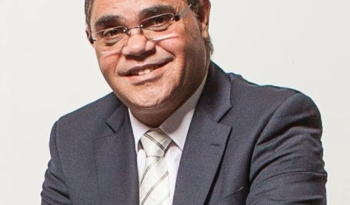 Aboriginal man in suit and wearing glasses.