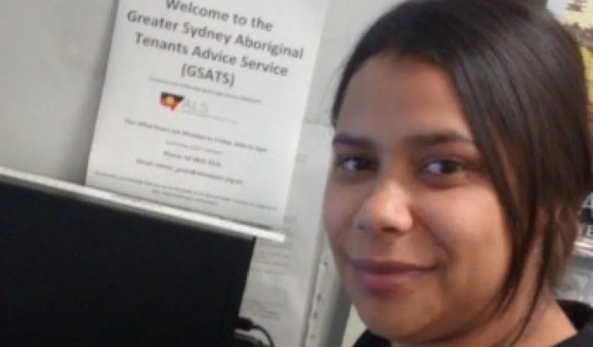 A close-up photo of a woman with black hair pulled back. In the background is a computer box and a certificate.