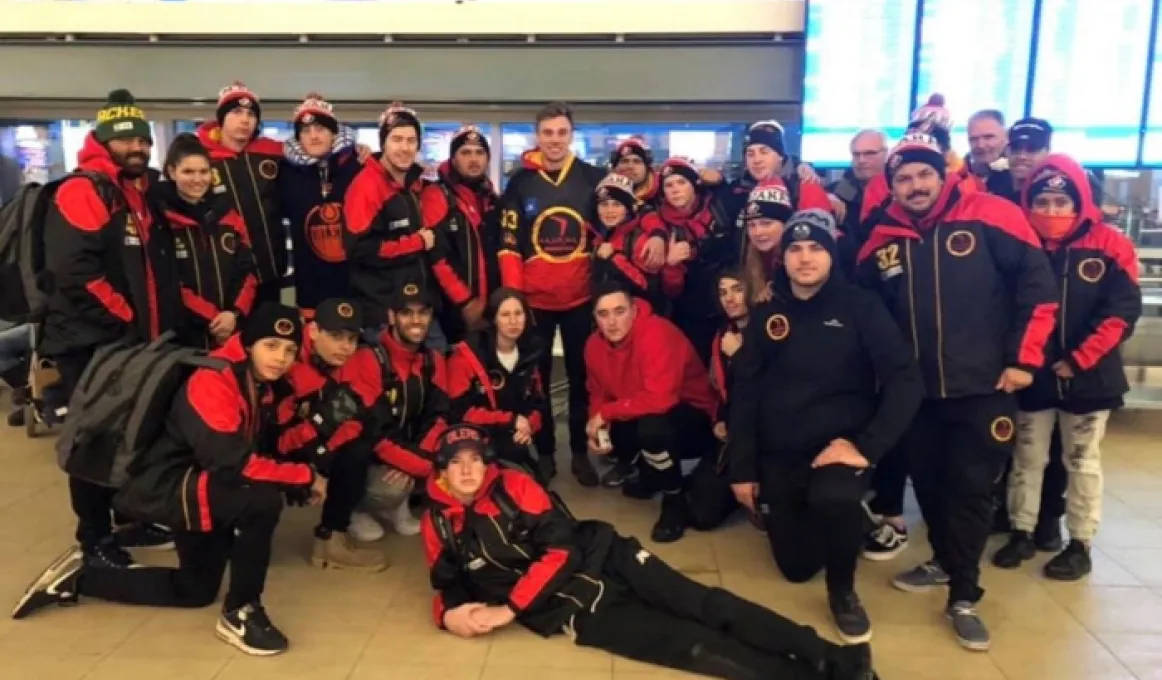 Image Alt text (for vision impaired readers)	A team of young Indigenous men and women wearing red and black jackets, black pants and red and black hats.