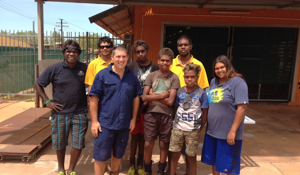 Students, school attendance officers and teacher standing in front of school workshop.