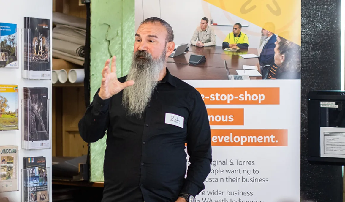 Wirra Hub Business Coach, Rob Barton speaking in front of a group of people with a Wirra Hub banner behind him.