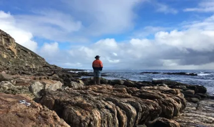 Man stands on rocks by the ocean