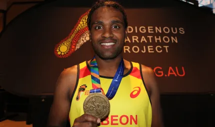 Indigenous male holding a medal.