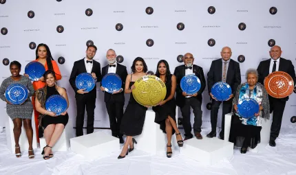 A group of 11 men and women in a row, they each hold an award.