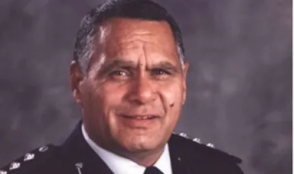 Head and shoulders shot of Indigenous man dressed in police officer’s uniform.