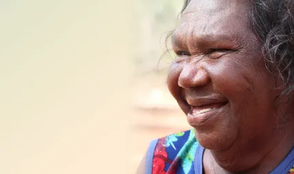 A smiling Aboriginal woman in a colourful top.