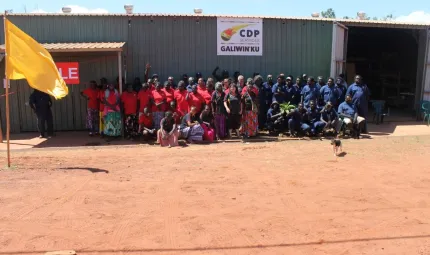 A large group of Aboriginal people standing out the front of a large shed.