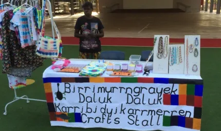 Jocelyn Koyole standing behind table of items for sale.