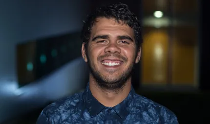 Aboriginal young man dressed in blue shirt. In the background is a light and doorway and some blue colours.