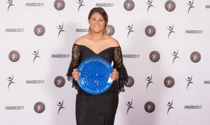 A young Aboriginal woman in evening wear holding a large blue plate.