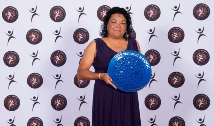 Indigenous woman Michelle Deshong holding blue plate shaped award.