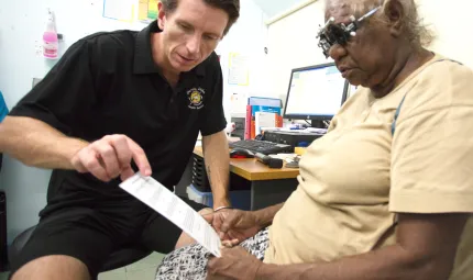 Optometrist Luke Arkapaw performing an eye check on an Indigenous woman