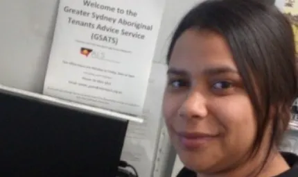 A close-up photo of a woman with black hair pulled back. In the background is a computer box and a certificate.