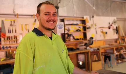 Man in safety vest stands in wood workshop