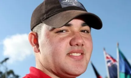 Smiling young man in brown cap and red shirt in close up shot.