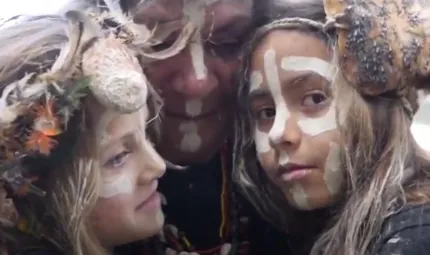 Head shot of two young girls with face paint and head-dresses with a mature woman between them also with face paint.