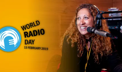 Indigenous woman with long hair in front of a microphone is smiling. Behind her is radio apparatus and to left is a blue and white logo and teh words World Radio Day 13 February 2019