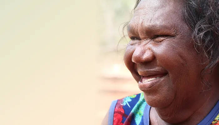 A smiling Aboriginal woman in a colourful top.