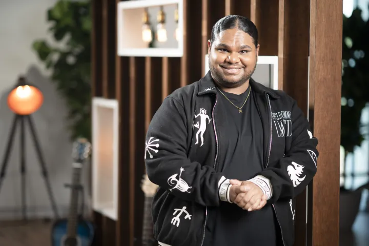 Australian Idol winner Royston Sagigi-Baira, a Torres Strait Islander man, wearing a black t-shirt and black jacket. He is smiling at the camera.