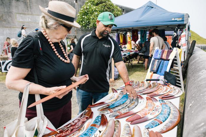 A man and woman standing in front of a market stall selling colourful Boomerangs
