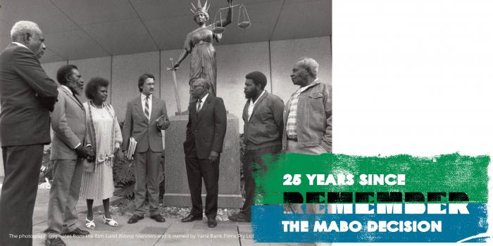 Five Indigenous men, one Indigenous woman and one non-Indigenous man stand in half circle in front of a statue of a woman holding a sword in the right hand and a set of scales in the left.  Words: 25 years since The Mabo Decision Remember