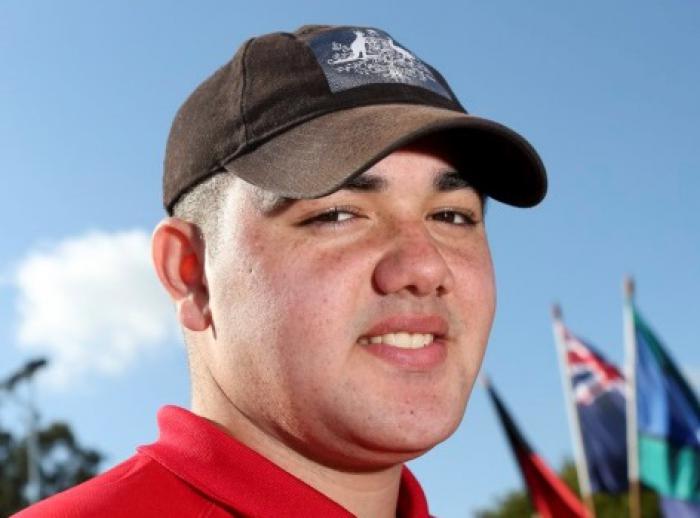 Smiling young man in brown cap and red shirt in close up shot.