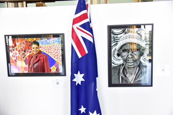 2 portraits of women sit aside the Australian flag.