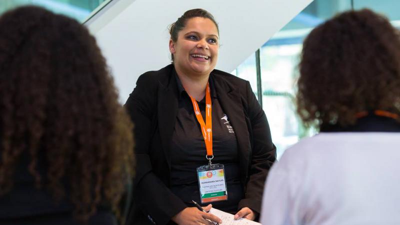 Indigenous woman and trainer Mundanara Bayles, sits in front of two people who face her and with their backs to camera