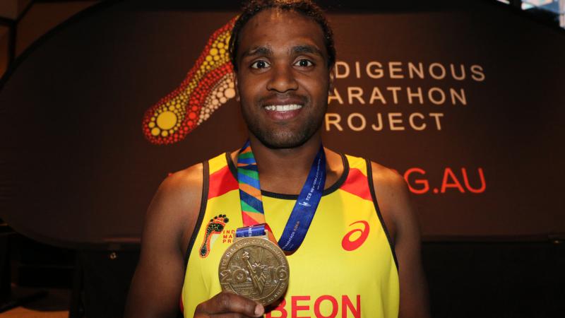 Indigenous male holding a medal.