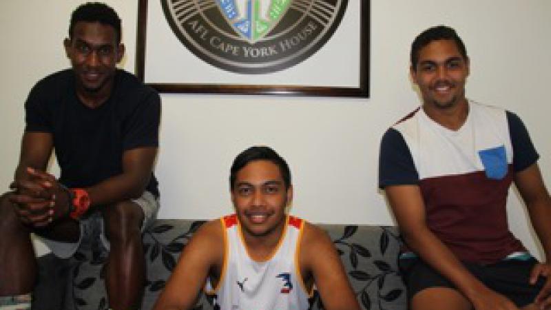 Three young Indigenous men sitting on a couch and smiling.