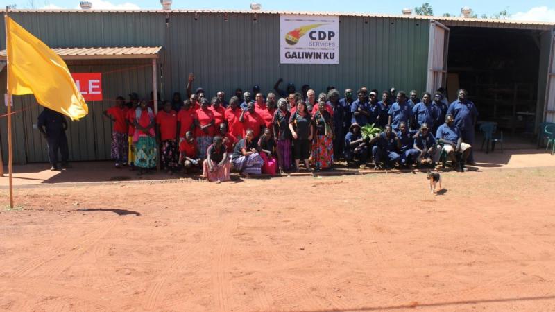 A large group of Aboriginal people standing out the front of a large shed.