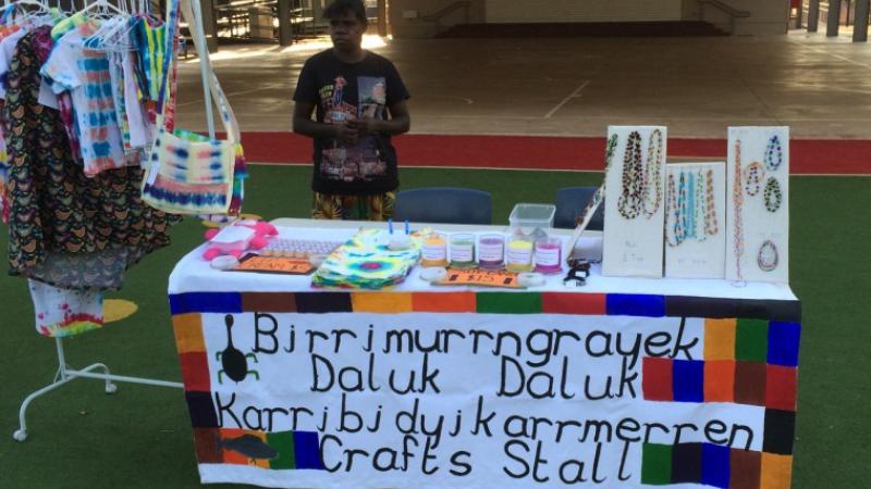 Jocelyn Koyole standing behind table of items for sale. 