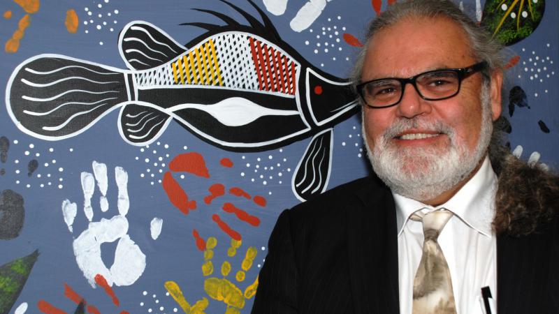 Founder & CEO of Nallawilli Technology, Roderick McLeod, stands in front of an indigenous painting