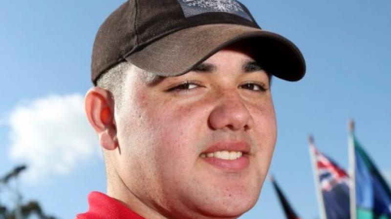 Smiling young man in brown cap and red shirt in close up shot.