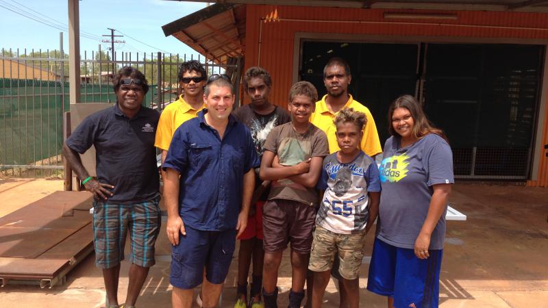 Students, school attendance officers and teacher standing in front of school workshop.