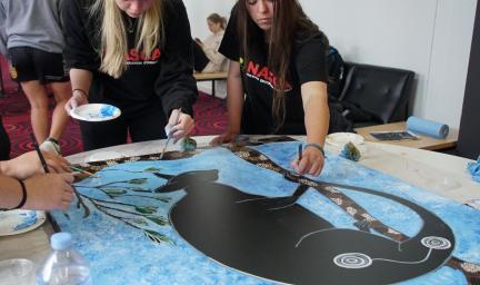 Participants at the NASCA NAIDOC Youth Conference painting together in a traditional style.