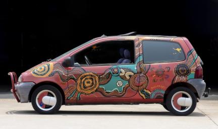 A small red car decorated with colourful dots and swirls. The word Balarinyi is painted beside the left back wheel.